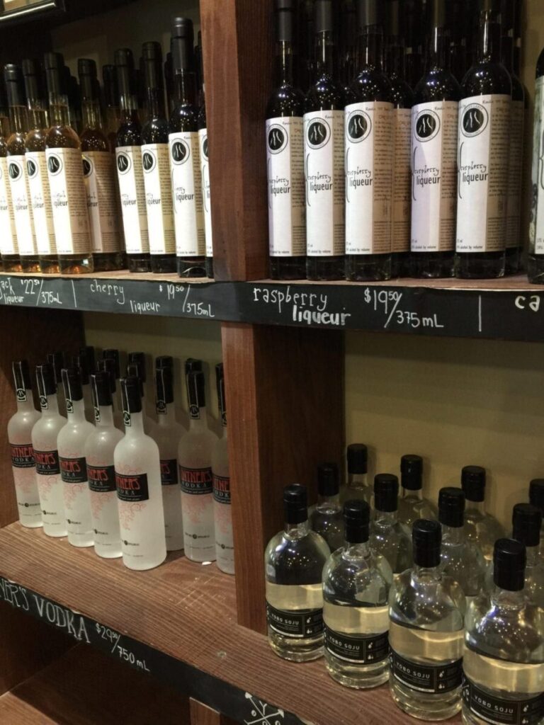A shelf filled with lots of bottles of alcohol including vodka.