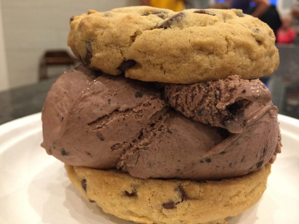 A cookie and ice cream sandwich on a white plate.