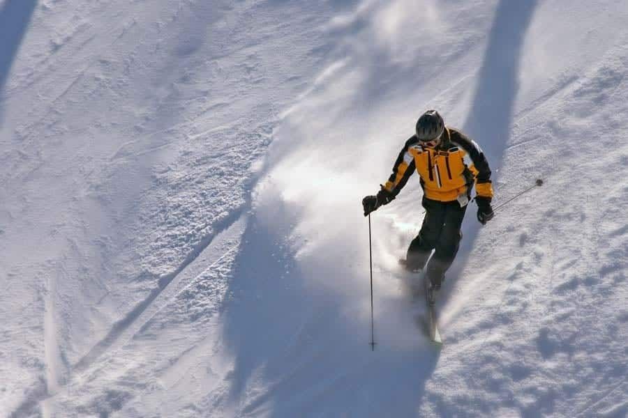 A man is skiing down a snow covered slope with the number 11 on his jacket.