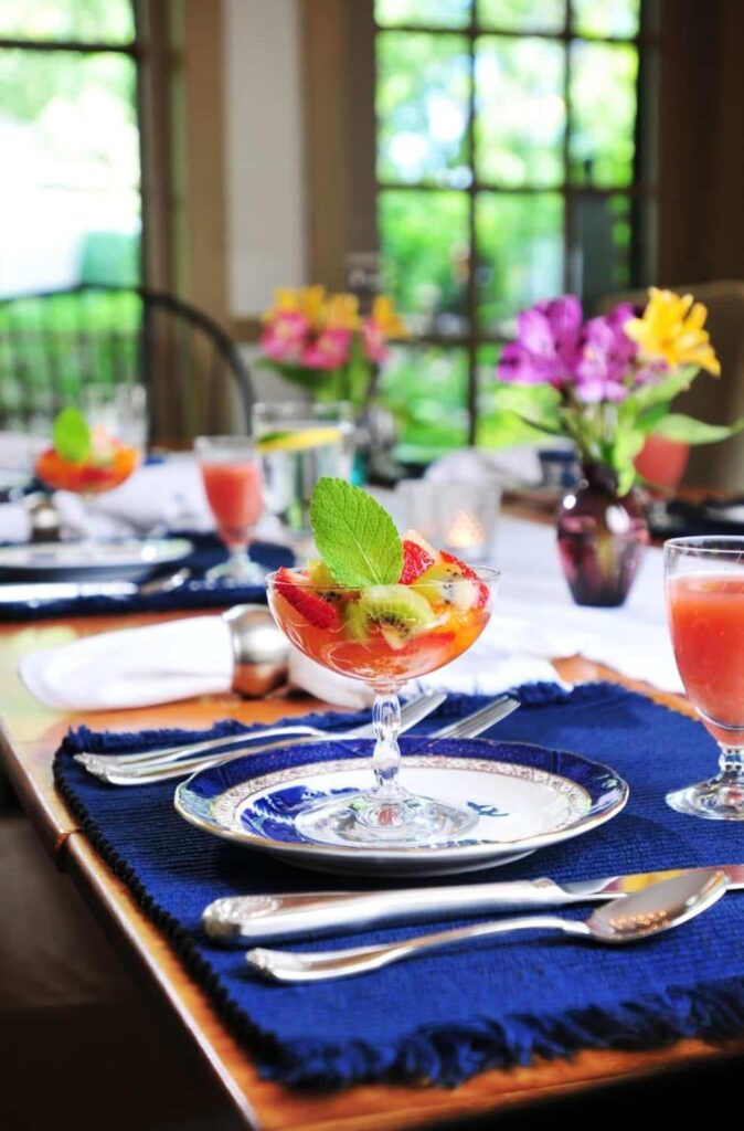 A bowl of fruit is on a plate on a table.