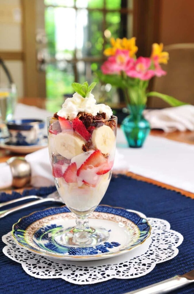 A dessert in a glass on a plate on a table.