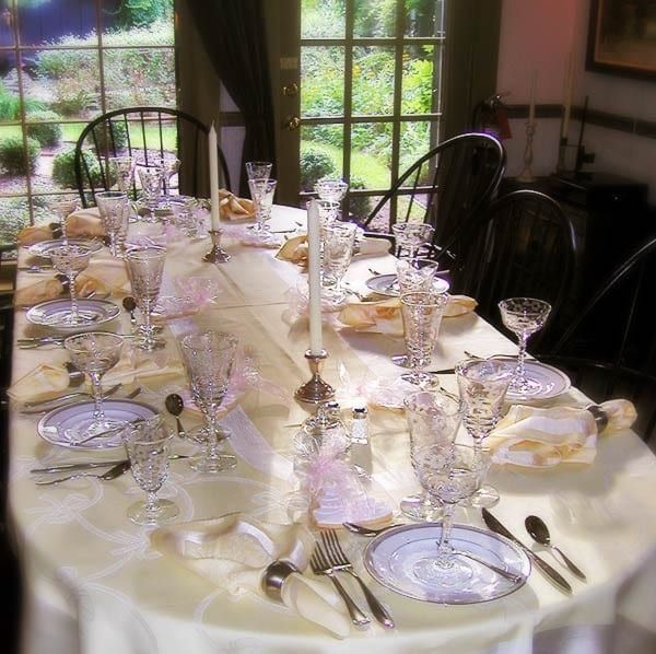 A long table with plates glasses and candles on it.