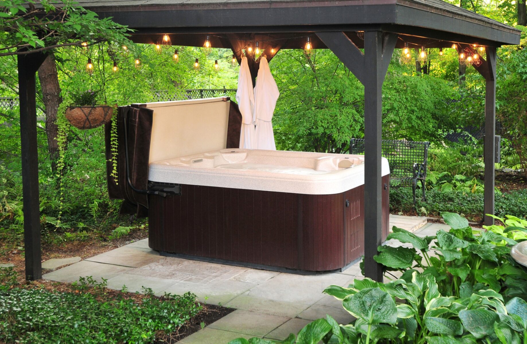 A hot tub is sitting under a canopy in the woods.